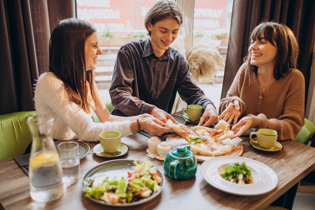 Troje przyjaciół dzieli się pizzą w kawiarni